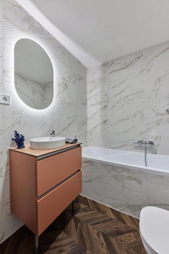 a bathroom with a sink and a tub and a mirror at The Amberlyn Suite Hotel in Budapest