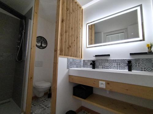 une salle de bain avec un lavabo et un miroir et des toilettes dans l'établissement Libération classé 3 étoiles, à Grandcamp-Maisy