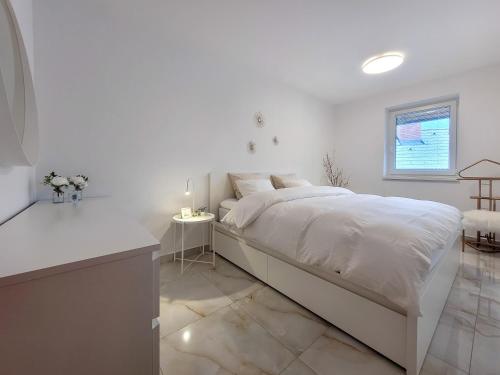 a white bedroom with a large bed and a table at Apartments Julian Experience in Rateče