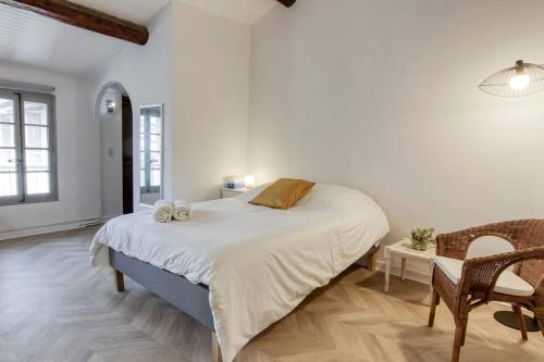 une chambre blanche avec un grand lit et une chaise dans l'établissement Noa - Mont Piete Studio intramuros -, à Avignon