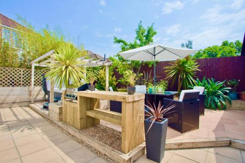 a patio with a table with an umbrella and plants at Luxurious Retreat - Hot Tub - Pool Table - Gym - Sauna - Cinema Room - Free Parking - WiFi - Close to Beach in Bournemouth