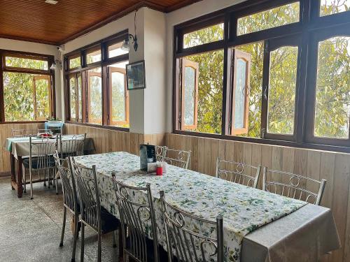 a dining room with a table and chairs and windows at The Di-Lac Retreat in Gangtok
