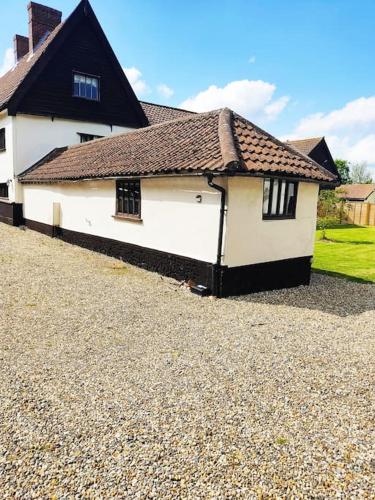 a white house with a black roof at The Retreat in Tibenham