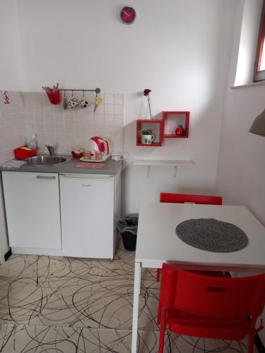 a kitchen with a sink and a table with red chairs at Rooms Sobe ZG in Zagreb