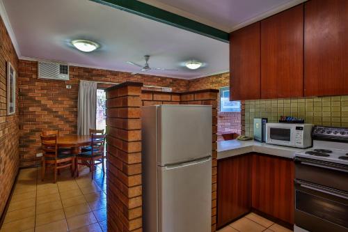a kitchen with a refrigerator, stove and microwave at Bayside Holiday Apartments in Broome