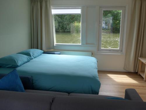 a bed in a room with a couch and a window at Apartment at the East side, close to center in Amsterdam