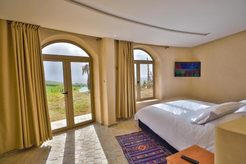 ein Schlafzimmer mit einem großen Bett und großen Fenstern in der Unterkunft Bhalil Farm House in Sefrou