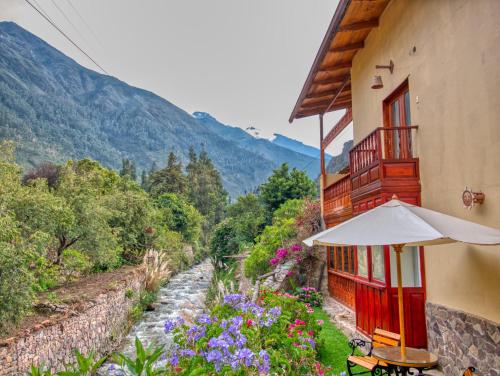 a building with an umbrella and flowers next to a river at Sol Ollantay Boutique Hotel in Ollantaytambo