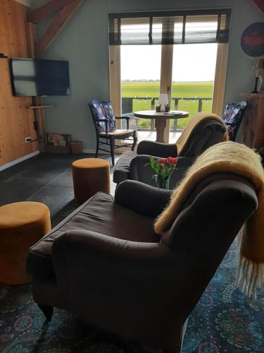 a living room with two couches and a tv at B&B De Verre Kijker in Barsingerhorn