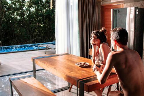 een man en een vrouw aan een tafel met een glas wijn bij Stylish Pool Villa - 10 Mins Walk To The Beach in Koh Lanta