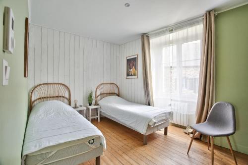 a bedroom with two beds and a window at Charmante maison bretonne pour 6, a Saint-Suliac in Saint-Suliac