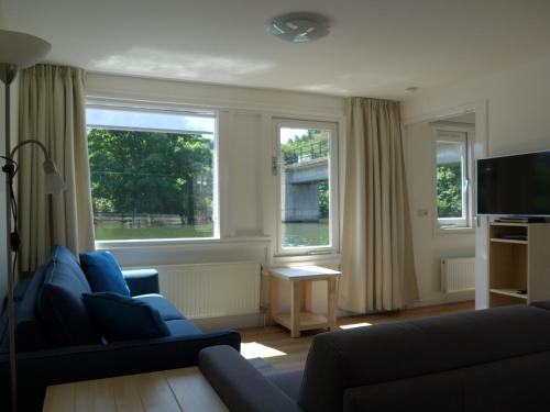 uma sala de estar com um sofá e duas janelas em Apartment at the East side, close to center em Amesterdão