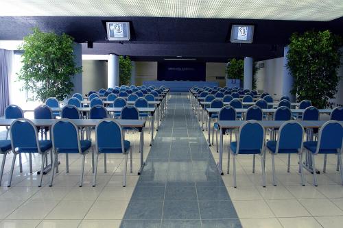 a room with blue chairs and tables and a stage at Grand Hotel Continental in Tirrenia