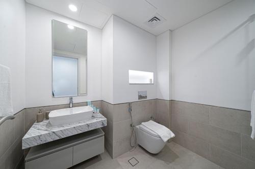 a white bathroom with a sink and a toilet at Classy One Bed, Burj Al Arab View, Beach Access in Dubai