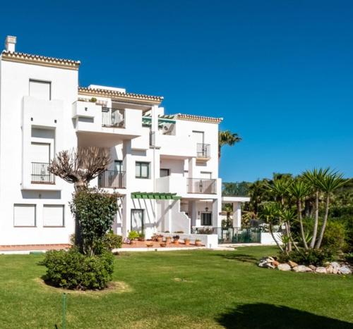 un gran edificio de apartamentos blanco con un patio verde en Alhaurin Golf Apartment en Alhaurín el Grande