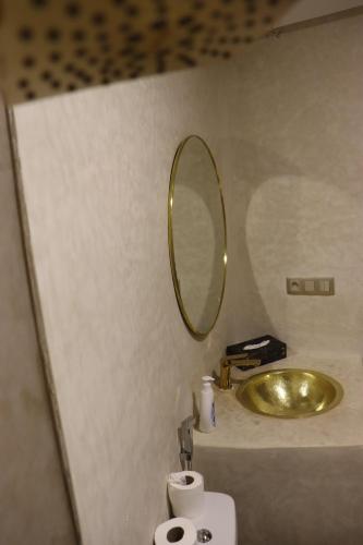 a bathroom with a gold sink and a mirror at Bhalil Farm House in Sefrou