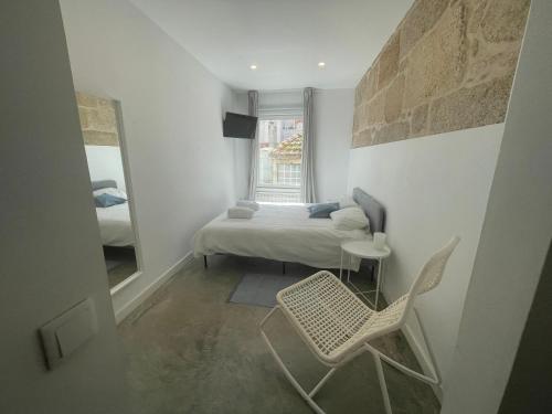 een slaapkamer met een bed, een spiegel en een stoel bij Corazón casco viejo in Vigo