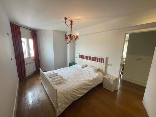 a bedroom with a white bed and a chandelier at No podrás olvidarlo in Baiona
