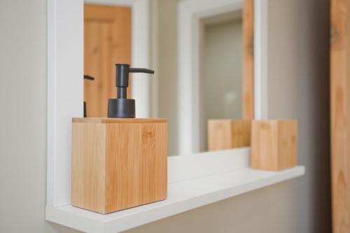 a wooden toothbrush holder sitting on a shelf in front of a mirror at Luxury Home - Hot Tub - Pool Table - Cinema Room - Close to Beach in Bournemouth