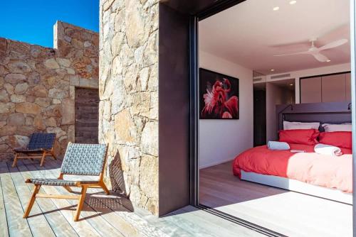 - une chambre avec un lit rouge et un mur en pierre dans l'établissement VILLA ISULA BELLA, à Porto-Vecchio
