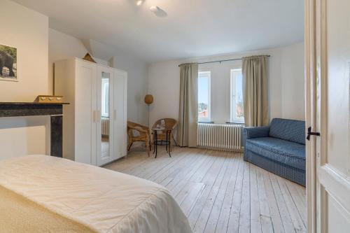 een slaapkamer met een bed en een blauwe bank bij Oceanide - Gerenoveerde luxe villa vlak bij het strand in De Haan