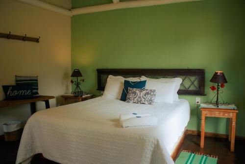 zieloną sypialnię z dużym łóżkiem i ręcznikami. w obiekcie Pousada Quinta do Barao w mieście Conceição da Ibitipoca