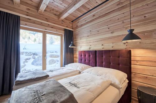 two beds in a wooden room with a window at Xeis Natur Apartments in Johnsbach