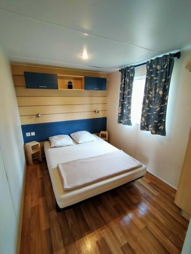 a bedroom with a white bed and wooden floors at Mobilhome in Boofzheim