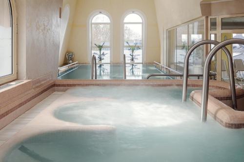 eine Whirlpool-Badewanne in einem Zimmer mit Fenstern in der Unterkunft Humboldt Park Hotel & Spa in Karlsbad