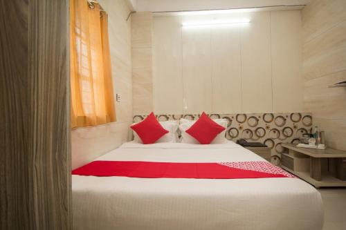 a bedroom with a large bed with red pillows at Capital O Hotel Priyanshu in Siliguri