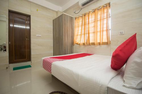 a bedroom with a bed with red pillows and a window at Super Capital O Priyanshu in Siliguri