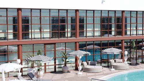a building with umbrellas and chairs and a swimming pool at Seth Port Ciutadella in Ciutadella