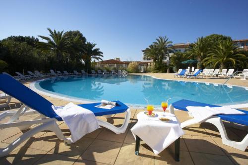 a swimming pool with blue and white chairs and a table at SOWELL RESIDENCES Les Perles du Golfe de Saint-Tropez in Grimaud