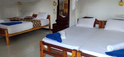 two twin beds in a room withthritisthritisthritisthritisthritisthritisthritisthritisthritis at SURF & SAND Hotel Arugambay in Arugam Bay