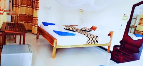 a bedroom with a white bed and a wooden chair at SURF & SAND Hotel Arugambay in Arugam Bay