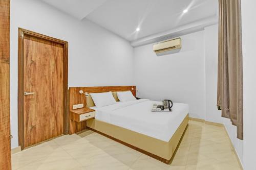 een slaapkamer met een wit bed en een houten deur bij OYO Townhouse 801 The Circle in Jaipur