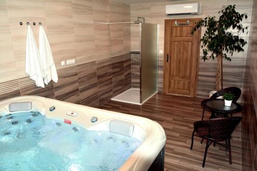 a jacuzzi tub in a bathroom with a table and a chair at Apartmány u Kotačků in Veverské Knínice