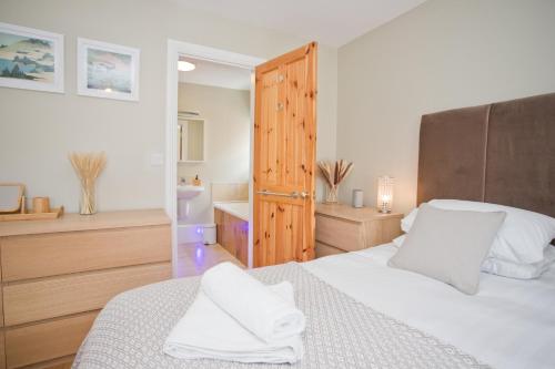 a bedroom with a white bed and a bathroom at Luxury Home - Hot Tub - Pool Table - Cinema Room - Close to Beach in Bournemouth