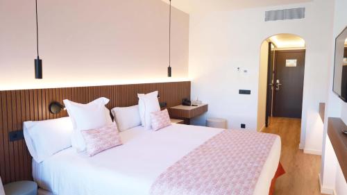 a bedroom with a large white bed with pink pillows at Seth Port Ciutadella in Ciutadella
