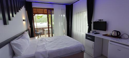 a bedroom with a bed and a television and a balcony at Kaptanhan Pansiyon in Kazıklı