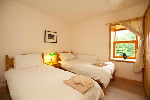 2 camas en una habitación con ventana en The Byre, Back Borland Holday Cottages en Stirling