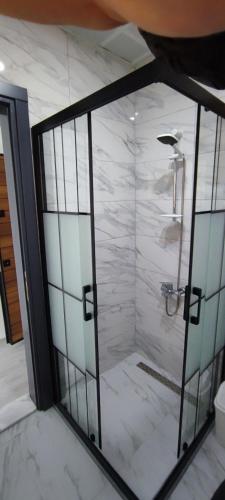 a shower with a glass door in a bathroom at Kaptanhan Pansiyon in Kazıklı