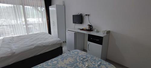 a small bedroom with a bed and a tv at Kaptanhan Pansiyon in Kazıklı