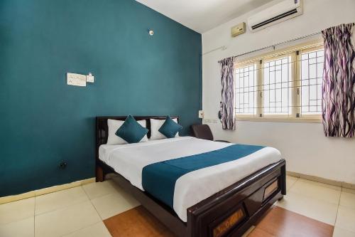 a bedroom with a large bed with blue walls at OYO SilverKey 2d Residency in Irugūr