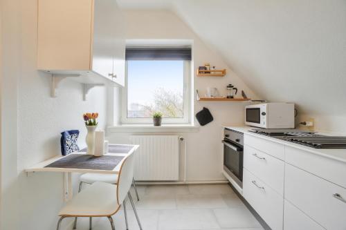a white kitchen with a table and a window at NICE TOPFLOOR STUDIO APARTMENT in Copenhagen