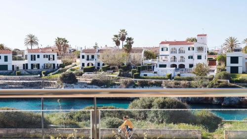a person riding a bike on a bridge with houses at Seth Port Ciutadella in Ciutadella