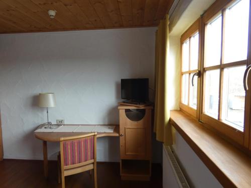 um quarto com uma secretária, uma televisão e uma janela em Kitz Alm Saarwellingen em Saarwellingen