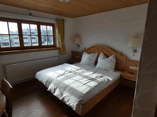 um quarto com uma cama com lençóis brancos e 2 janelas em Kitz Alm Saarwellingen em Saarwellingen