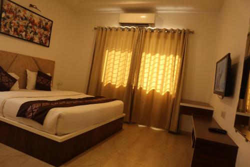 a bedroom with a bed and a window with curtains at Hotel Grand Ecotel, Aurangabad in Aurangabad