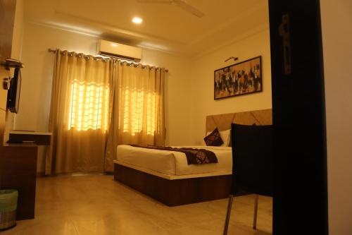 a bedroom with a bed and a window with curtains at Hotel Grand Ecotel, Aurangabad in Aurangabad